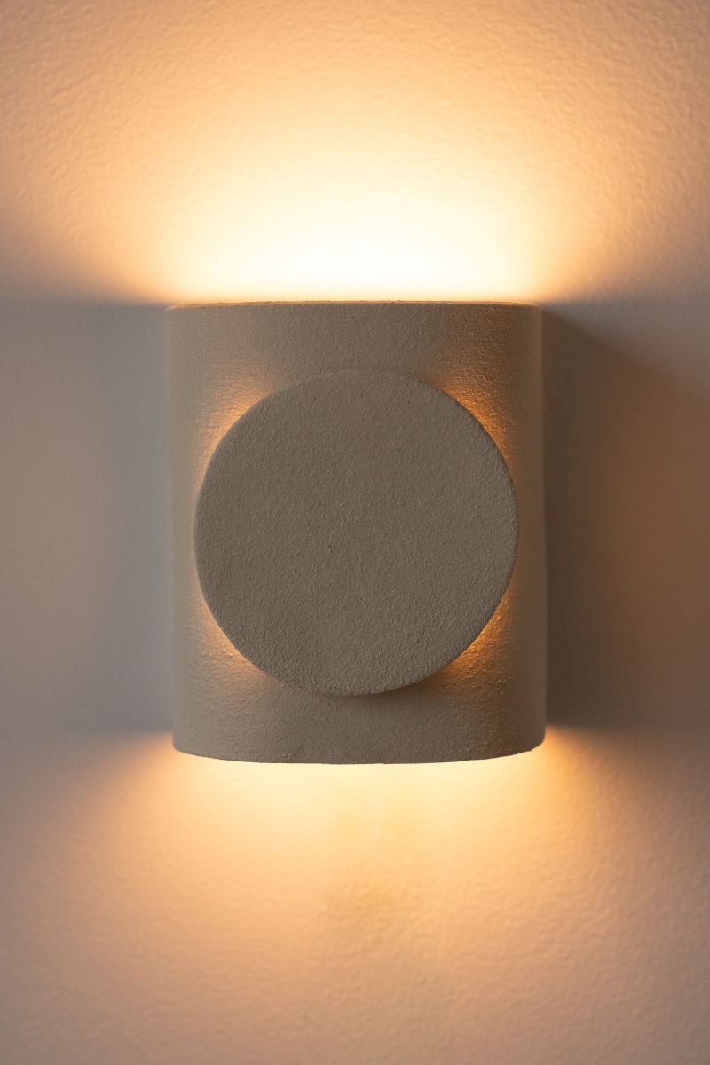 L'applique Tini Chams réalisée selon la technique de la plaque offre plusieurs sorties de lumière. Signifiant petit soleil en arabe, Tini Chams est fabriquée avec du grès blanc chamotté, terre lisse à laquelle a été rajoutée de la terre cuite broyée lui donnant une texture idéale pour le modelage et un grain authentique.