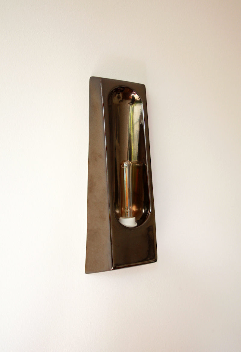 Alliance de l'artisanat et du design contemporain, les appliques Alcove de Violaine d'Harcourt sont fabriquées en céramique émaillée au Portugal, dans une région où le travail de l'argile est une tradition ancestrale. Leur forme s'inspire de l'élément architectural auquel elles ont emprunté leur nom - l'alcôve - qui évoque une ambiance intimiste et feutrée. Au centre de l'applique, une élégante ampoule tubulaire diffuse une lumière tamisée qui sublime les émaux aux teintes naturelles.&nbsp;