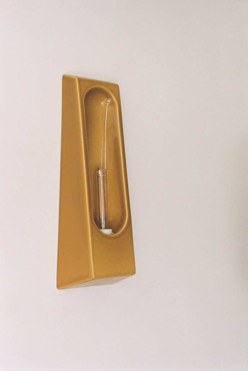 Alliance de l'artisanat et du design contemporain, les appliques Alcove de Violaine d'Harcourt sont fabriquées en céramique émaillée au Portugal, dans une région où le travail de l'argile est une tradition ancestrale. Leur forme s'inspire de l'élément architectural auquel elles ont emprunté leur nom - l'alcôve - qui évoque une ambiance intimiste et feutrée. Au centre de l'applique, une élégante ampoule tubulaire diffuse une lumière tamisée qui sublime les émaux aux teintes naturelles.&nbsp;