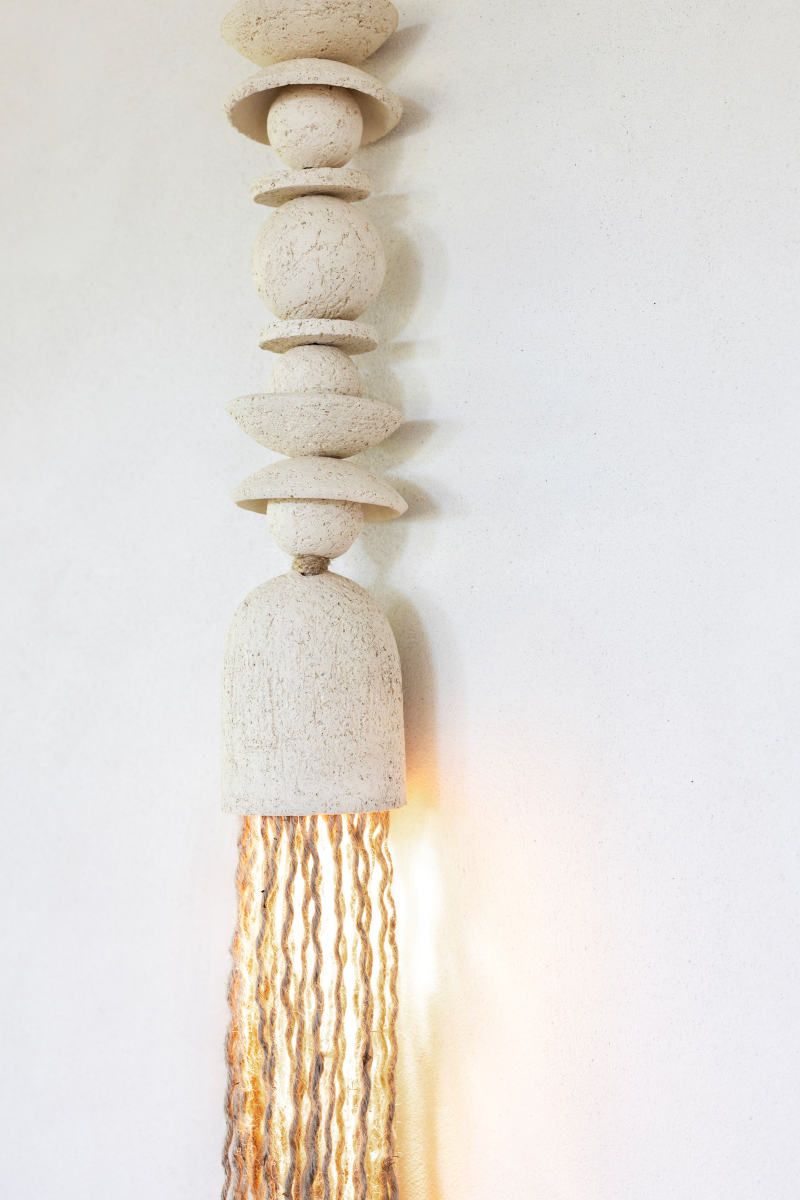 Zulu est une suspension lumineuse originale confectionnée par Atelier HD en exclusivité pour Caroline Andréoni La Maison Alliant artisanat et design intemporel, sa structure en céramique délicatement façonnée à la main est habillée de floches élégantes en coton, dissimulant subtilement le câble électrique pour une esthétique épurée. Les floches, disposées autour du spot, ajoutent une touche texturée et organique qui contraste harmonieusement avec la pureté de la céramique.