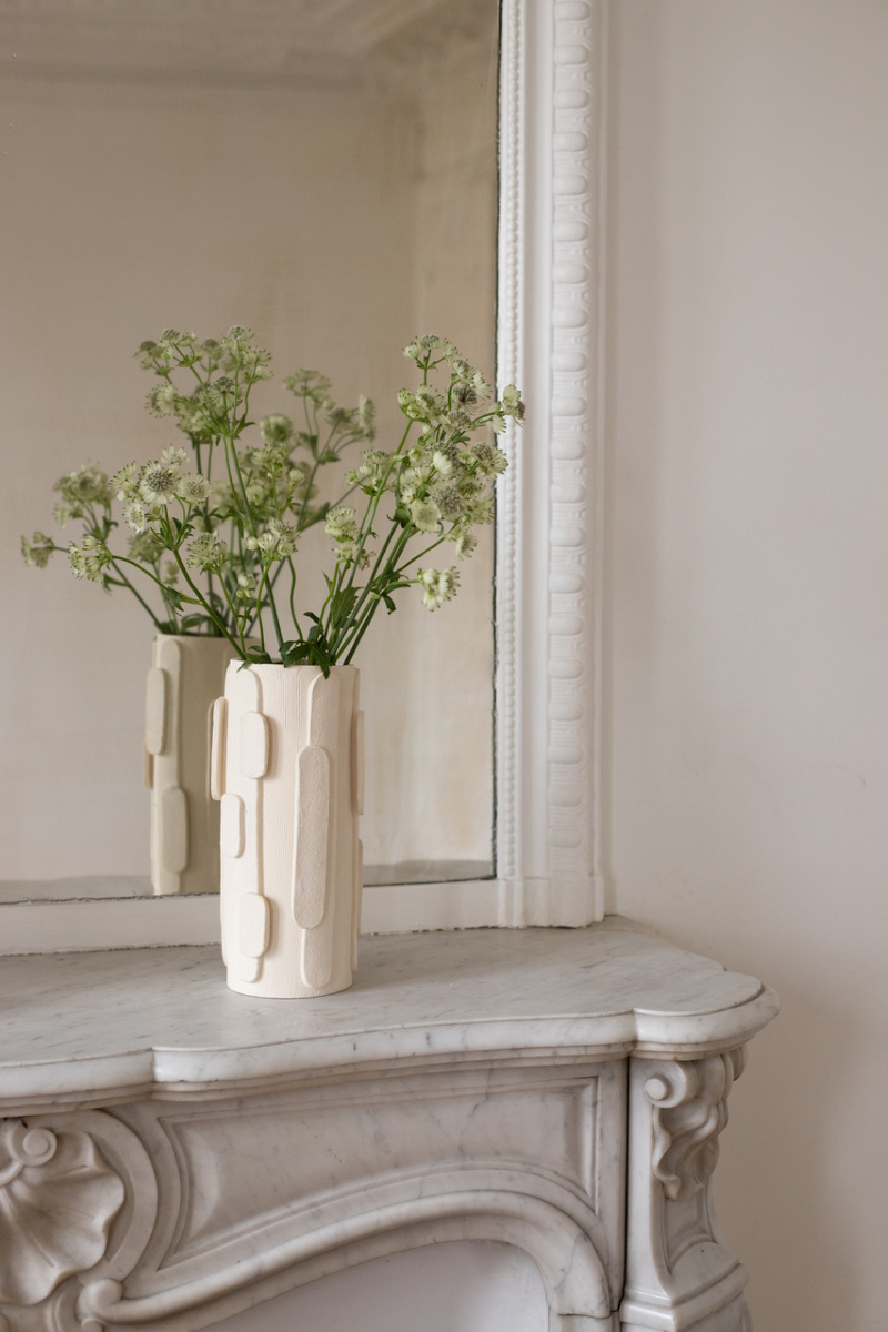 Le bougeoir Glow en exclusivité chez Caroline Andréoni La Maison tire son nom de l'éclat qu'il apporte, en anglais, évoquant ainsi la luminosité naturelle qui inspire infatigablement la créatrice Adeline Delesalle. Ce vase en grand modèle est réalisé selon la technique de la plaque, résultat du savoir-faire de l'artiste, entièrement réalisé à la main dans ses ateliers en France. Les cylindres sont "griffés" afin de créer un contraste de matière entre le support et les éléments ajoutés.