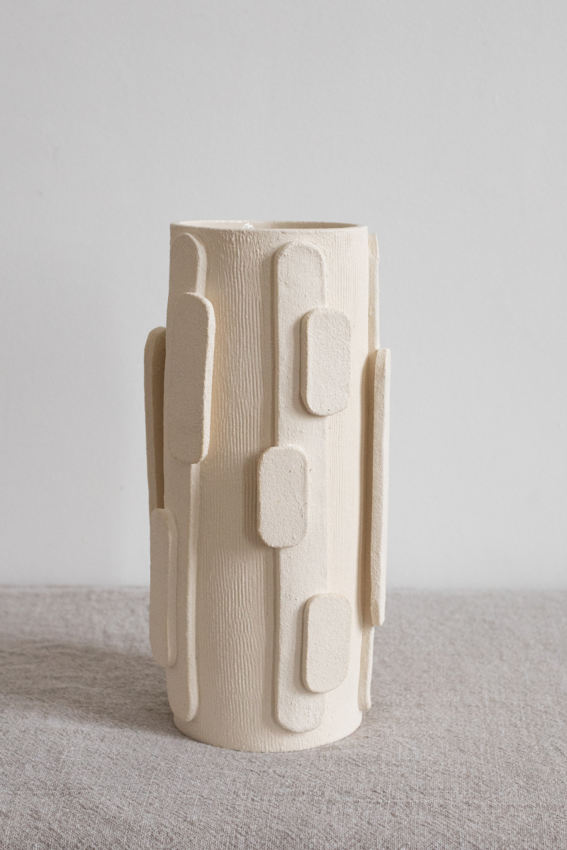 Le bougeoir Glow en exclusivité chez Caroline Andréoni La Maison tire son nom de l'éclat qu'il apporte, en anglais, évoquant ainsi la luminosité naturelle qui inspire infatigablement la créatrice Adeline Delesalle. Ce vase en grand modèle est réalisé selon la technique de la plaque, résultat du savoir-faire de l'artiste, entièrement réalisé à la main dans ses ateliers en France. Les cylindres sont "griffés" afin de créer un contraste de matière entre le support et les éléments ajoutés.