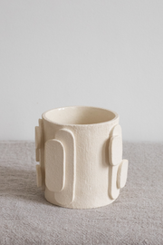 Le bougeoir Glow en exclusivité chez Caroline Andréoni La Maison tire son nom de l'éclat qu'il apporte, en anglais, évoquant ainsi la luminosité naturelle qui inspire infatigablement la créatrice Adeline Delesalle. Ce vase en petit modèle est réalisé selon la technique de la plaque, résultat du savoir-faire de l'artiste, entièrement réalisé à la main dans ses ateliers en France. Les cylindres sont "griffés" afin de créer un contraste de matière entre le support et les éléments ajoutés.