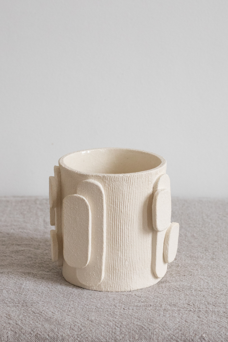 Le bougeoir Glow en exclusivité chez Caroline Andréoni La Maison tire son nom de l'éclat qu'il apporte, en anglais, évoquant ainsi la luminosité naturelle qui inspire infatigablement la créatrice Adeline Delesalle. Ce vase en petit modèle est réalisé selon la technique de la plaque, résultat du savoir-faire de l'artiste, entièrement réalisé à la main dans ses ateliers en France. Les cylindres sont "griffés" afin de créer un contraste de matière entre le support et les éléments ajoutés.