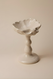 Cette coupelle sur pied, délicatement inspirée des formes de coquillage, fait partie de notre collection art de la table. Elle peut servir pour un dessert ou même comme écrin pour bijoux.

Chaque pièce est produite à la main et à la commande dans notre atelier marseillais, ce qui rend chacune singulière : de légères variations de taille, de forme ou de texture témoignent du travail artisanal.