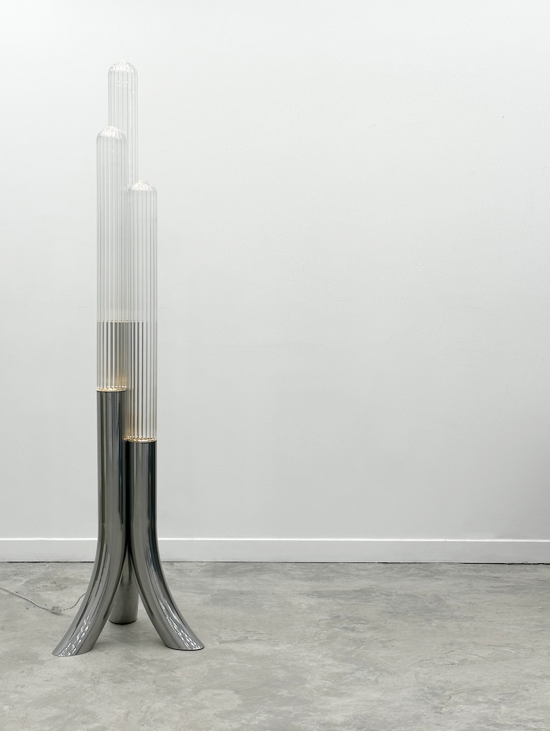 La rencontre de Mickaël avec un artisan verrier lui permet de retranscrire toutes les nuances d'oscillations et de reflets auxquels le paysage méditerranéen l'a habitué. Des cannes striées, fumées ou transparentes assemblées sous la forme d'un cactus élancé et raffiné, qui révèlent toute leur singularité en s'éclairant.  Tous les reliefs du verre sont projetés sur l'environnement qui l'entoure. Une ode au territoire d'origine de Mickaël.