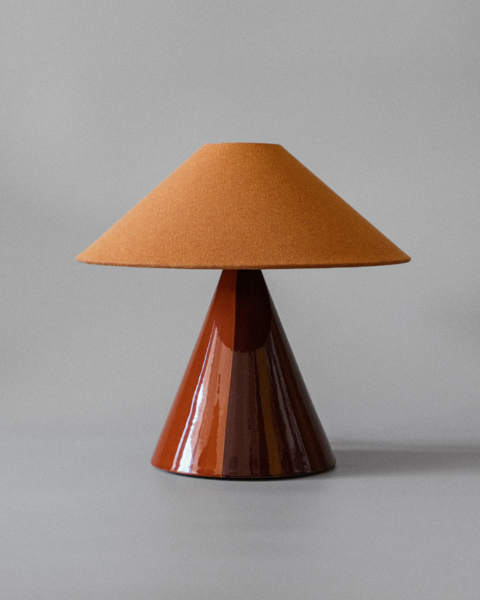 Basé dans le sud de la France, le duo mère-fille à l'origine de Mattina Moderna apporte leurs racines italiennes à la lampe à poser Caterina.

Dotée d'un design bicolore peint à la main et d'un abat-jour tonkinois en tissu de coton, cette lampe de table élégante et minimaliste résulte en une combinaison totalement unique de couleurs et de textures, rendant chaque pièce unique en son genre.