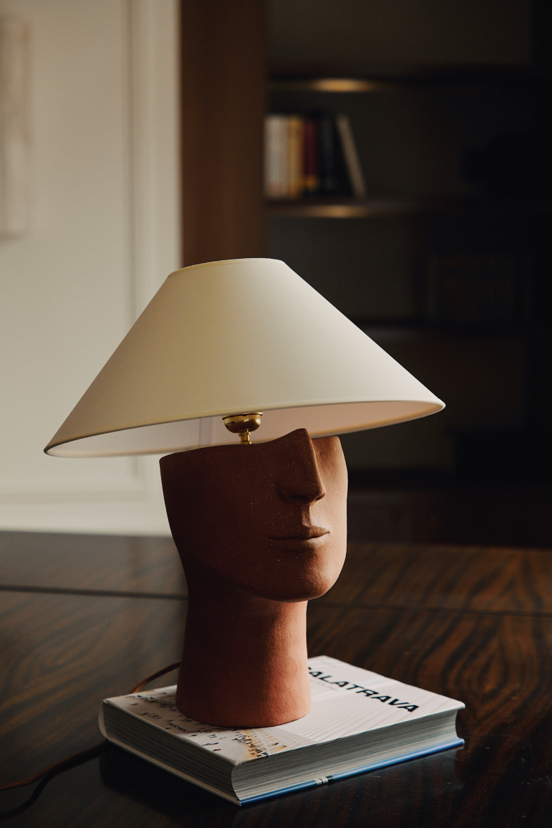 Fabriquée à base de grès orange brut chamotté, la lampe à poser Audacieuse reprend un visage affirmé. Cette pièce fait partie du duo de lampes "Les Sœurs" proposé par l'artiste Thalia Dalecky.