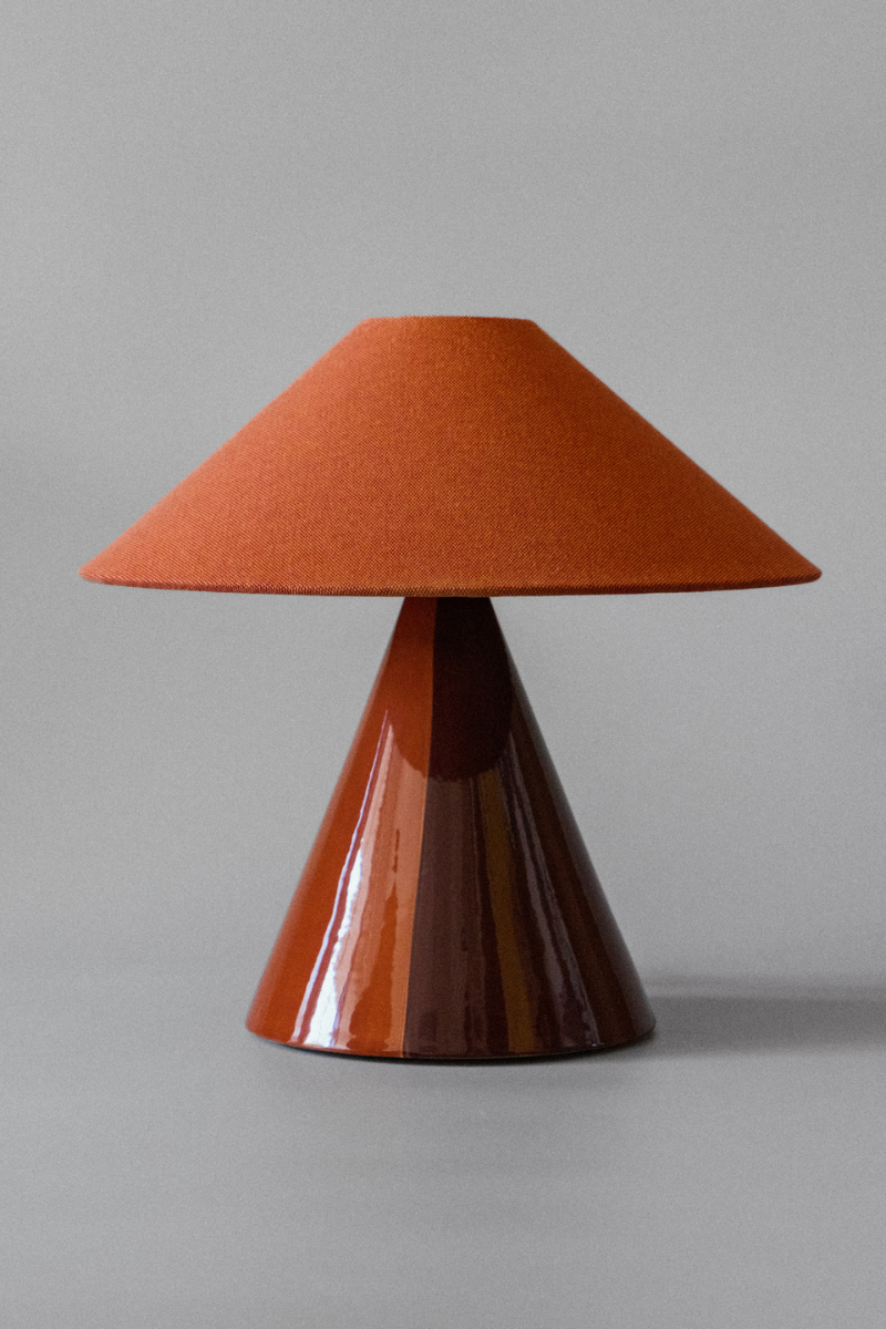 Basé dans le sud de la France, le duo mère-fille à l'origine de Mattina Moderna apporte leurs racines italiennes à la lampe à poser Caterina.

Dotée d'un design bicolore peint à la main et d'un abat-jour tonkinois en tissu de coton, cette lampe de table élégante et minimaliste résulte en une combinaison totalement unique de couleurs et de textures, rendant chaque pièce unique en son genre.