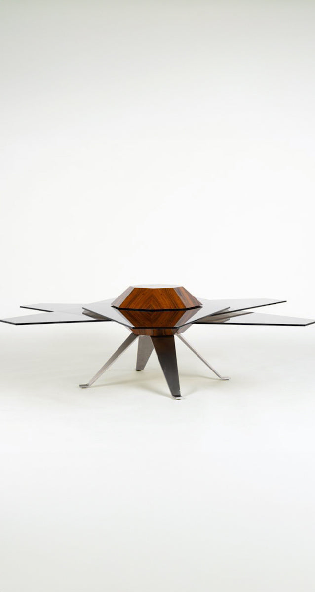 Corps céleste. Atterrissage en douceur pour ce module tabulaire inspiré par Saturne.&nbsp;De forme elliptique ou circulaire, Starsky s’adapte aux envies et habille un intérieur de façon sculpturale. Bien campée sur des pieds en inox massif et son corps en Palissandre Dos Santos, cette table modulable offre de nombreuses options grâce à ses lamelles de verre mobiles&nbsp;qui se déploient tels des panneaux solaires en fonction du nombre de convives.