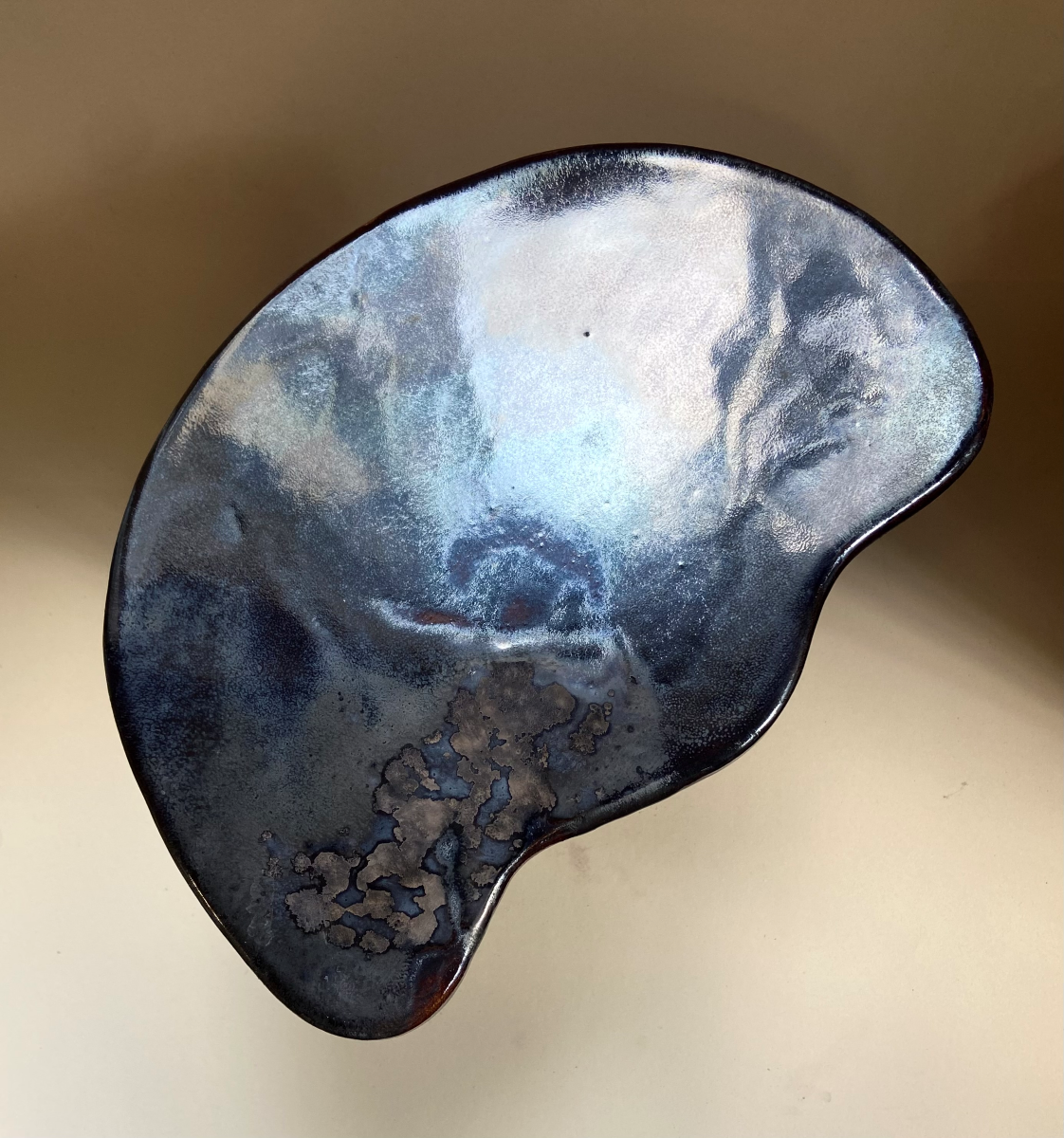 Petite table d'appoint Tempête au design épuré réalisé en céramique à effets métallisés sur le plateau et noir. Cette pièce, réalisée par l'artiste Thalia Dalecky, présente des ornages sur le pied.