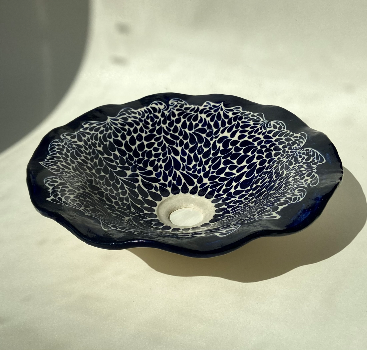 La vasque à poser Acqua en grès chamotté couleur crème par l'artiste Thalia Dalecky est  peinte minutieusement à la main en bleu nuit. Cette pièce incarne une élégance raffinée en associant la profondeur du bleu à des accents de crème.