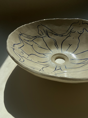 L'artiste Thalia Dalecky propose une vasque à poser "Danseuses" représentant des nus féminins dessinés à la main de couleur bleu nuit. Cette œuvre elle honore toutes les femmes qui l’entourent de près ou de loin : celles qui ont quelque chose à dire, celles qui se battent, qui se sont battues et celles qui sont en paix. Avec un diamètre entre 38 et 42 centimètres et une hauteur de 15 centimètres, cette vasque est travaillée avec du grès blanc, un émail transparent brillant et une peinture bleu océan.