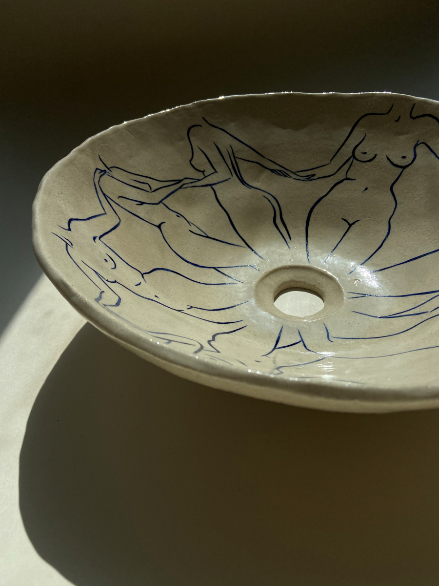 L'artiste Thalia Dalecky propose une vasque à poser "Danseuses" représentant des nus féminins dessinés à la main de couleur bleu nuit. Cette œuvre elle honore toutes les femmes qui l’entourent de près ou de loin : celles qui ont quelque chose à dire, celles qui se battent, qui se sont battues et celles qui sont en paix. Avec un diamètre entre 38 et 42 centimètres et une hauteur de 15 centimètres, cette vasque est travaillée avec du grès blanc, un émail transparent brillant et une peinture bleu océan.