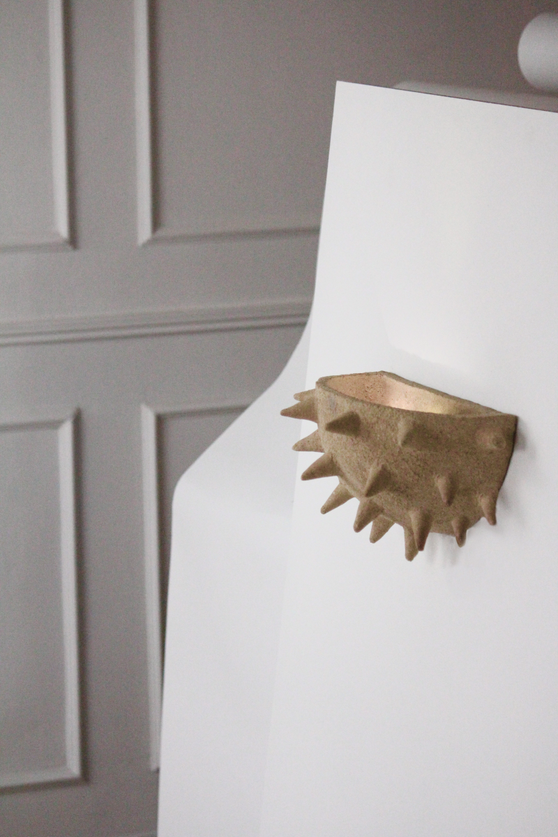 Cette applique Jupiter constituée de grès chamotte présente une texture avec des grains de sable. Chaque pièce est unique, numérotée, signée et modelée manuellement dans un grès chamotte, une argile cuite plusieurs fois entre 900 et 1400 degrés. Au cours de ce processus, l'objet devient aussi solide que la pierre. C'est par l'assemblage, le modelage, la sculpture et les différentes cuissons que l'objet se révèle.

Grâce à la céramique, Alan Louis capture l’essence de l’élégance brute et naturelle.