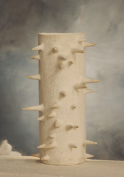 Cette applique Ostentus constituée de grès chamotte présente une texture avec des grains de sable.&nbsp;Chaque pièce est unique, numérotée, signée et modelée manuellement dans un grès chamotte, une argile cuite plusieurs fois entre 900 et 1400 degrés.

Grâce à la céramique, Alan Louis capture l’essence particulière de l’élégance brute et naturelle.