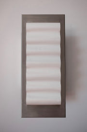 Les appliques Frame Alu Brut de Violaine d'Harcourt sont fabriquées à la main au Portugal, en aluminium et papier.

Dotées d'un design minimaliste et rendant un subtil hommage à l'architecture moderne, les appliques murales Frame sont réalisées avec des matériaux contrastés qui rehaussent le toucher doux d'une vague de papier.