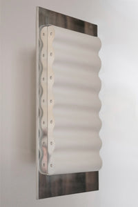 Les appliques Frame Acier Miroir de Violaine d'Harcourt sont fabriquées à la main au Portugal, en acier laqué argenté et en papier.

Dotées d'un design minimaliste et rendant un subtil hommage à l'architecture moderne, les appliques murales Frame sont réalisées avec des matériaux contrastés qui rehaussent le toucher doux d'une vague de papier.