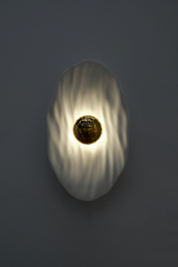 Façonnée à la main, l’applique Vesta associe un disque en faïence émaillée doré 24K, à une structure en plâtre sculpté aux lignes organiques.

Conçue comme une offrande à la lumière, Vesta rend hommage à la déesse du foyer. Elle diffuse une lumière douce et enveloppante, idéale pour instaurer une atmosphère apaisante et sacrée.