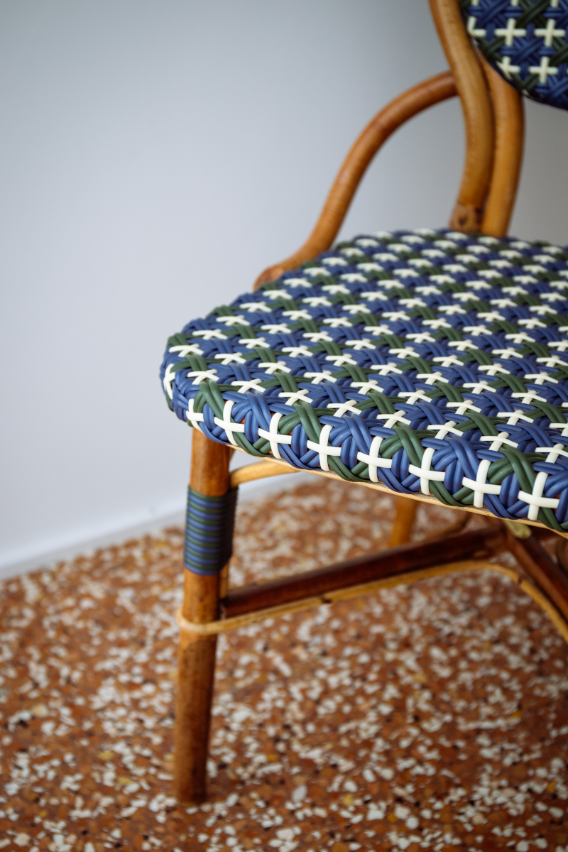 La chaise Odette fait la part belle au rotin. Le Second Empire a vu se développer le métier de rotinier et a été l’âge d’or de ce matériau. Le rotin est une tige de palmier importée des forêts tropicales asiatiques à l’époque coloniale. La chaise de bistro en rotin symbolise à elle seule les terrasses parisiennes et la gaieté de la capitale française. La forme florale et l’utilisation de matières végétales pour le design de la chaise Odette est une référence au catleya.