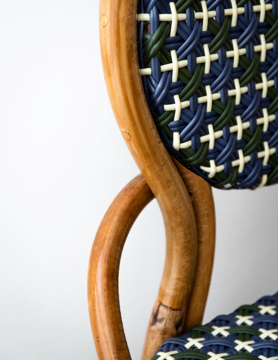 La chaise Odette fait la part belle au rotin. Le Second Empire a vu se développer le métier de rotinier et a été l’âge d’or de ce matériau. Le rotin est une tige de palmier importée des forêts tropicales asiatiques à l’époque coloniale. La chaise de bistro en rotin symbolise à elle seule les terrasses parisiennes et la gaieté de la capitale française. La forme florale et l’utilisation de matières végétales pour le design de la chaise Odette est une référence au catleya.