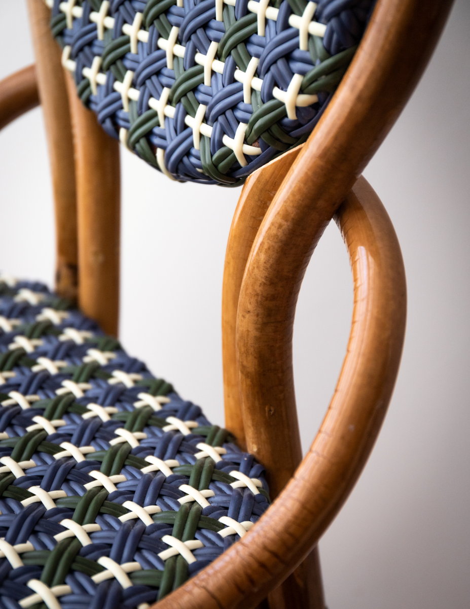 La chaise Odette fait la part belle au rotin. Le Second Empire a vu se développer le métier de rotinier et a été l’âge d’or de ce matériau. Le rotin est une tige de palmier importée des forêts tropicales asiatiques à l’époque coloniale. La chaise de bistro en rotin symbolise à elle seule les terrasses parisiennes et la gaieté de la capitale française. La forme florale et l’utilisation de matières végétales pour le design de la chaise Odette est une référence au catleya.