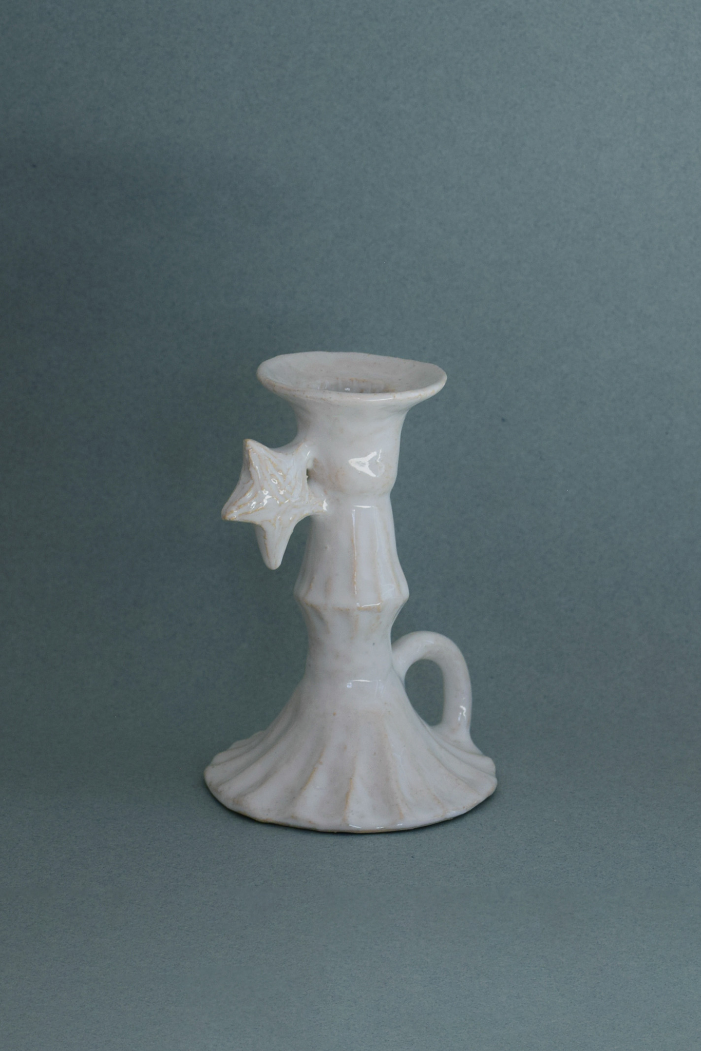 Le Petit Chandelier, issu de la collection Pierrot, évoque l’univers tendre et mélancolique du célèbre clown rêveur. Son modelage, tout en douceur, rend hommage à la nuit et à ses étoiles en s'inspirant de la célèbre comptine Au Clair de la Lune. Qu’il éclaire une table de chevet ou un coin de salon, Le Petit Chandelier incarne une poésie discrète. Façonné entièrement à la main, chaque bougeoir présente des irrégularités subtiles qui témoignent d'un geste instinctif.


Pièce unique, fabriquée à la main en r