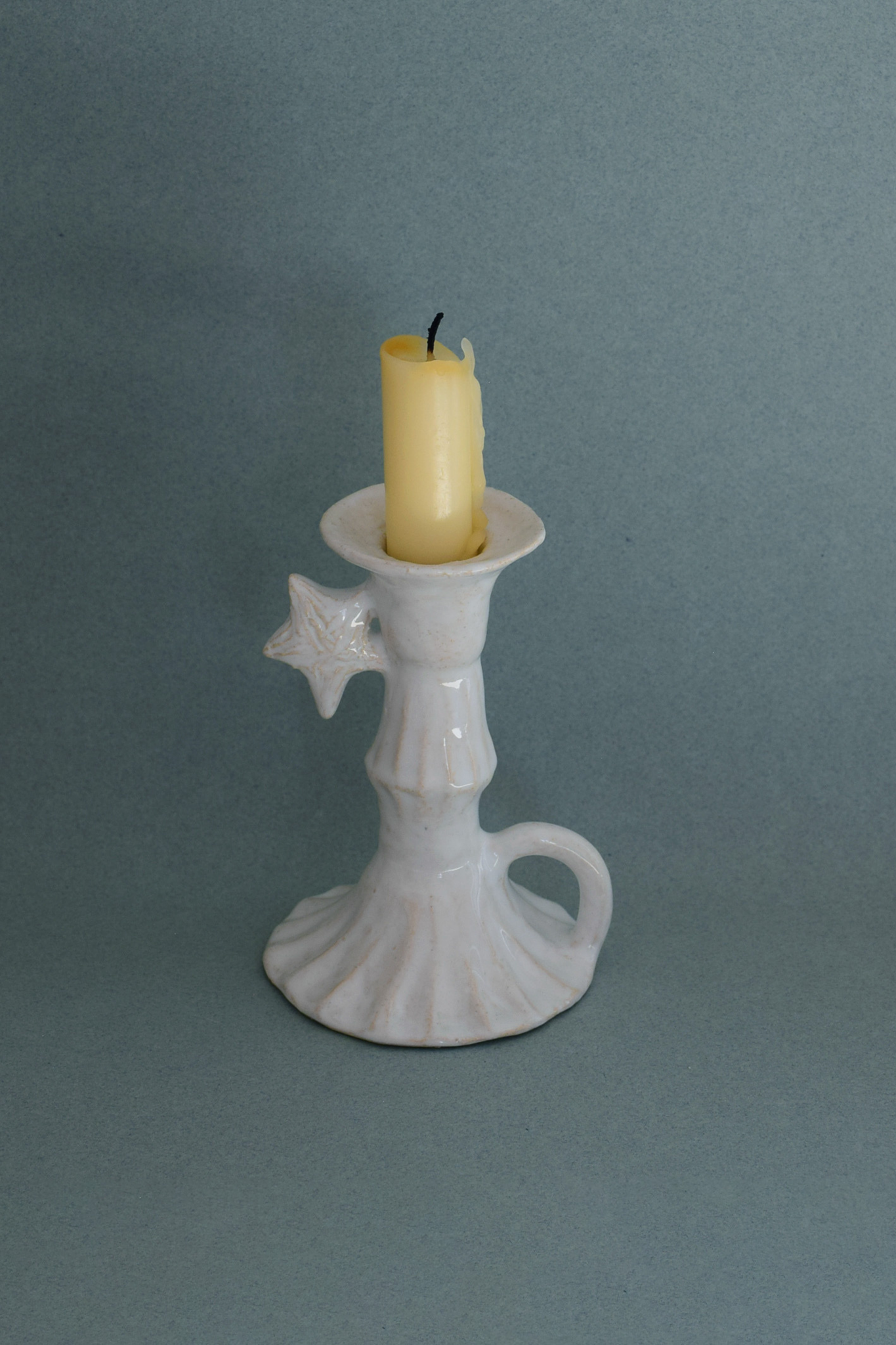 Le Petit Chandelier, issu de la collection Pierrot, évoque l’univers tendre et mélancolique du célèbre clown rêveur. Son modelage, tout en douceur, rend hommage à la nuit et à ses étoiles en s'inspirant de la célèbre comptine Au Clair de la Lune. Qu’il éclaire une table de chevet ou un coin de salon, Le Petit Chandelier incarne une poésie discrète. Façonné entièrement à la main, chaque bougeoir présente des irrégularités subtiles qui témoignent d'un geste instinctif.


Pièce unique, fabriquée à la main en r