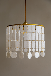 La suspension Ananke a été pensée et dessinée en interne par leur studio de création basé en Normandie. Inspiré par la nacre, cette pièce a été souhaitée comme une composition de petites pièces élégamment assemblées à la main.

Ses modules sont fabriqués en Île-de-France dans un atelier artisanal, confectionnant la matière première avec un savoir-faire local et responsable. Ce matériau unique et noble est issu de filières biosourcées et minérales (coquillages), initialement destinées au rebut.