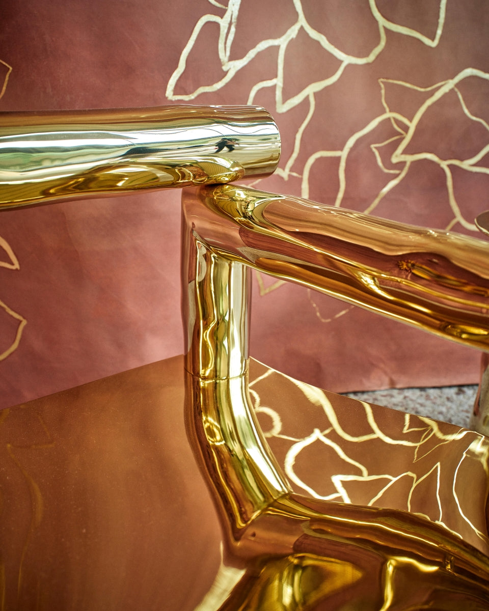 Bobi est un fauteuil sculptural en laiton poli miroir, non verni. Composé de tubes de laiton formés manuellement dans un dialogue entre lignes franches et courbes organiques, il associe structure et poésie.

Son assise, une tôle de laiton de 4 mm formée à la main, offre un confort enveloppant grâce à ses ondulations. Son aspect miroir crée une expérience sensorielle unique : l’assise se drape de son environnement, déformant la réalité et fascinant la perception.