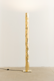 Hélios est un lampadaire sculptural en laiton poli miroir, non verni. Sa source lumineuse, dissimulée, diffuse une lumière douce vers le haut. Entièrement formée, soudée et polie à la main, chaque pièces de cette série sont uniques. Le reflet de sa hauteur dans son socle crée une illusion de mouvement, d’infini, un jeu de perceptions où le vertige s’invite. Hélios transforme l’espace, oscillant entre objet fonctionnel et œuvre sculpturale.