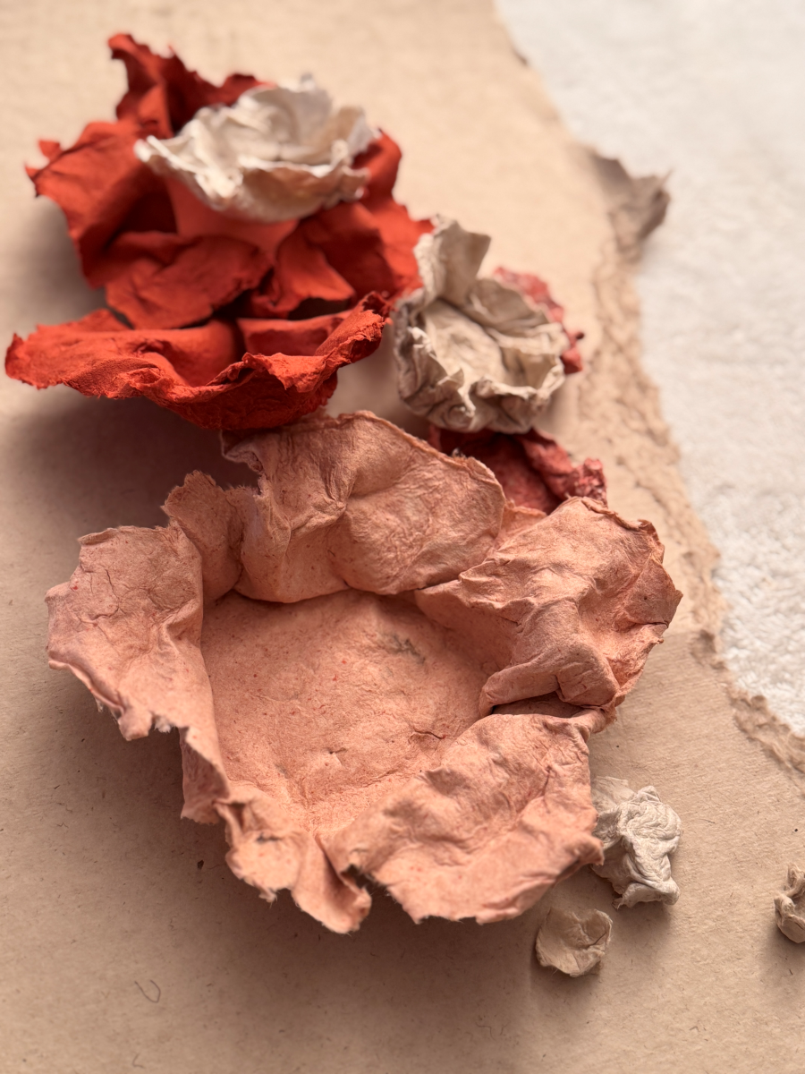 Pour cette lampe à poser Eclosion, Emma Karila utilise une technique de modelage où chaque détail est façonné à la main avec soin. La structure de base est recouverte d’une pâte de papier, ce qui lui donne cette texture un peu rugueuse, presque minérale.

Les fleurs sont créées une par une, avec différentes épaisseurs et couleurs, puis fixées sur la lampe. Cela donne un effet vraiment naturel et organique.