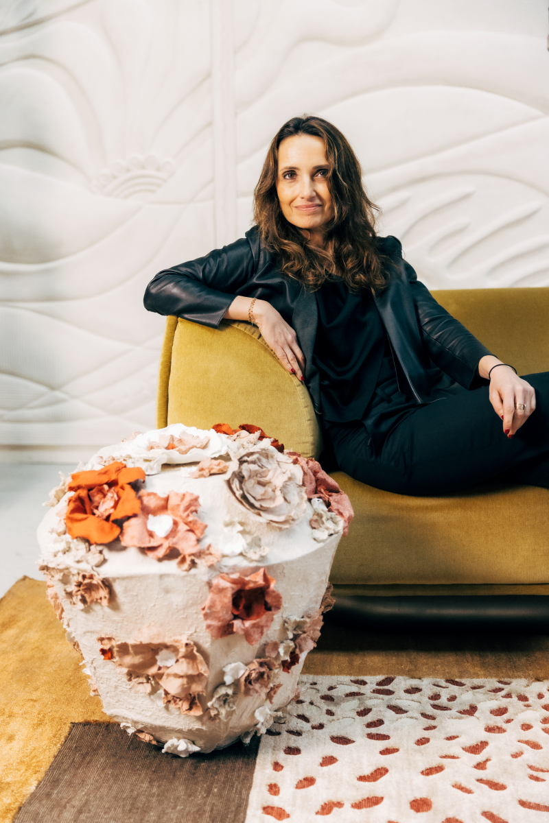 Pour cette lampe à poser Eclosion, Emma Karila utilise une technique de modelage où chaque détail est façonné à la main avec soin. La structure de base est recouverte d’une pâte de papier, ce qui lui donne cette texture un peu rugueuse, presque minérale.

Les fleurs sont créées une par une, avec différentes épaisseurs et couleurs, puis fixées sur la lampe. Cela donne un effet vraiment naturel et organique.