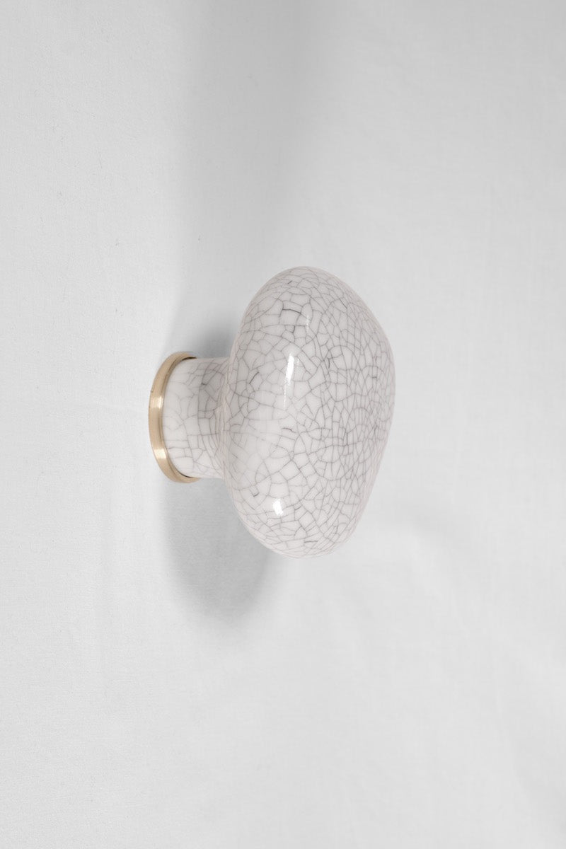 La patère Agate tire son nom de la pierre précieuse éponyme. Chaque patère possède sa propre personnalité, accentuée par les émaux cristallisés ou colorés qui s’harmonisent avec sa forme douce et organique, reflétant la diversité des teintes présentes dans les pierres d’Agate.  Son design intemporel et organique évoque la beauté et la simplicité des galets, tandis que sa délicate base est ornée d’une bague en laiton brossé.