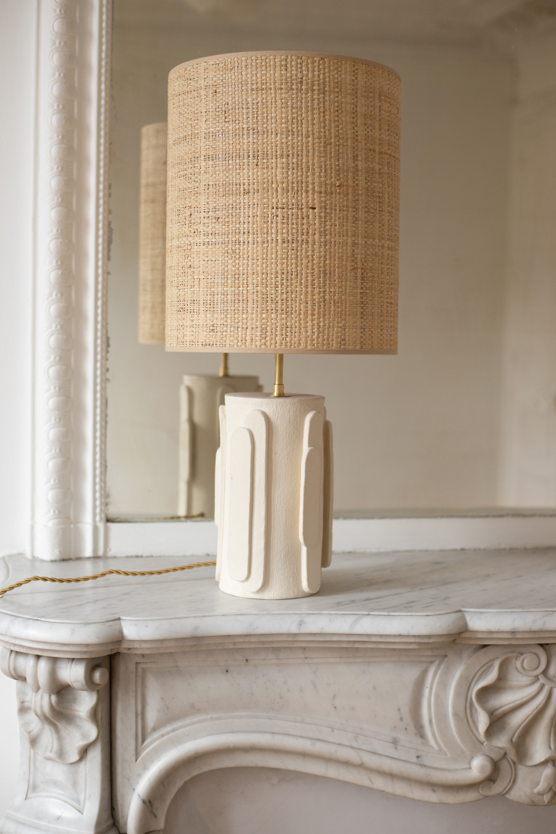 La lampe Glow en exclusivité chez Caroline Andréoni La Maison, tire son nom de l'éclat qu'il apporte, en anglais, évoquant ainsi la luminosité naturelle qui inspire infatigablement la créatrice Adeline Delesalle. Cette lampe est réalisée selon la technique de la plaque, résultat du savoir-faire de l'artiste, entièrement réalisée à la main dans ses ateliers en France. Les cylindres sont "griffés" afin de créer un contraste de matière entre le support et les éléments ajoutés.