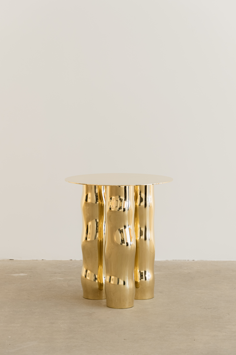 Mimo est une table d’appoint en laiton poli miroir, non verni. Sa structure repose sur une intention formelle simple : trois pieds et un plateau. Ses pieds, formés de manière organique, contrastent avec la ligne fine et délicate de son plateau.

La surface polie capte la lumière et reflète l’environnement, révélant l’élégance contenue dans la simplicité. Le laiton, travaillé à la main, invite à une expérience sensorielle où la matière et l’espace entrent en conversation.