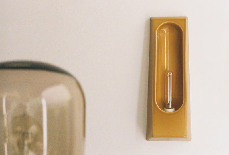 Alliance de l'artisanat et du design contemporain, les appliques Alcove de Violaine d'Harcourt sont fabriquées en céramique émaillée au Portugal, dans une région où le travail de l'argile est une tradition ancestrale. Leur forme s'inspire de l'élément architectural auquel elles ont emprunté leur nom - l'alcôve - qui évoque une ambiance intimiste et feutrée. Au centre de l'applique, une élégante ampoule tubulaire diffuse une lumière tamisée qui sublime les émaux aux teintes naturelles.&nbsp;