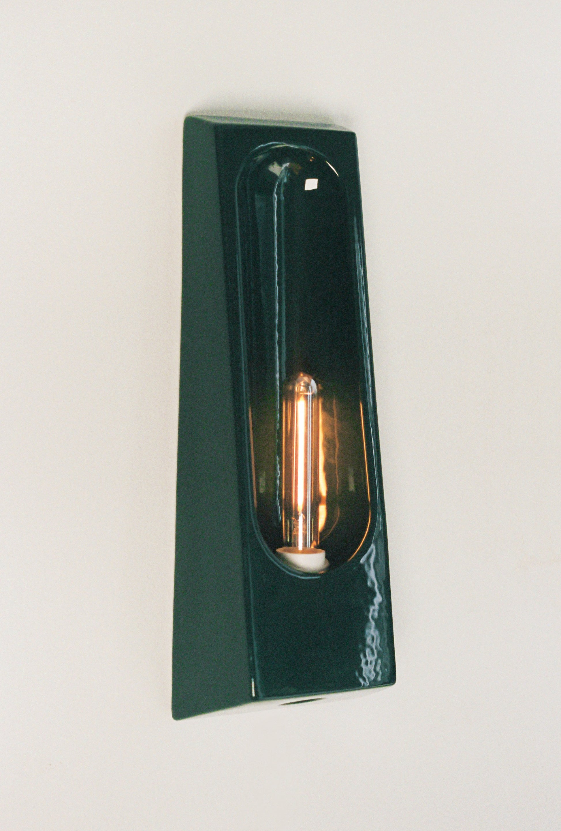 Alliance de l'artisanat et du design contemporain, les appliques Alcove de Violaine d'Harcourt sont fabriquées en céramique émaillée au Portugal, dans une région où le travail de l'argile est une tradition ancestrale. Leur forme s'inspire de l'élément architectural auquel elles ont emprunté leur nom - l'alcôve - qui évoque une ambiance intimiste et feutrée. Au centre de l'applique, une élégante ampoule tubulaire diffuse une lumière tamisée qui sublime les émaux aux teintes naturelles.&nbsp;