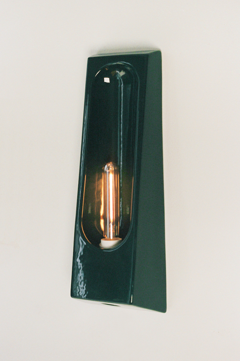 Alliance de l'artisanat et du design contemporain, les appliques Alcove de Violaine d'Harcourt sont fabriquées en céramique émaillée au Portugal, dans une région où le travail de l'argile est une tradition ancestrale. Leur forme s'inspire de l'élément architectural auquel elles ont emprunté leur nom - l'alcôve - qui évoque une ambiance intimiste et feutrée. Au centre de l'applique, une élégante ampoule tubulaire diffuse une lumière tamisée qui sublime les émaux aux teintes naturelles.&nbsp;