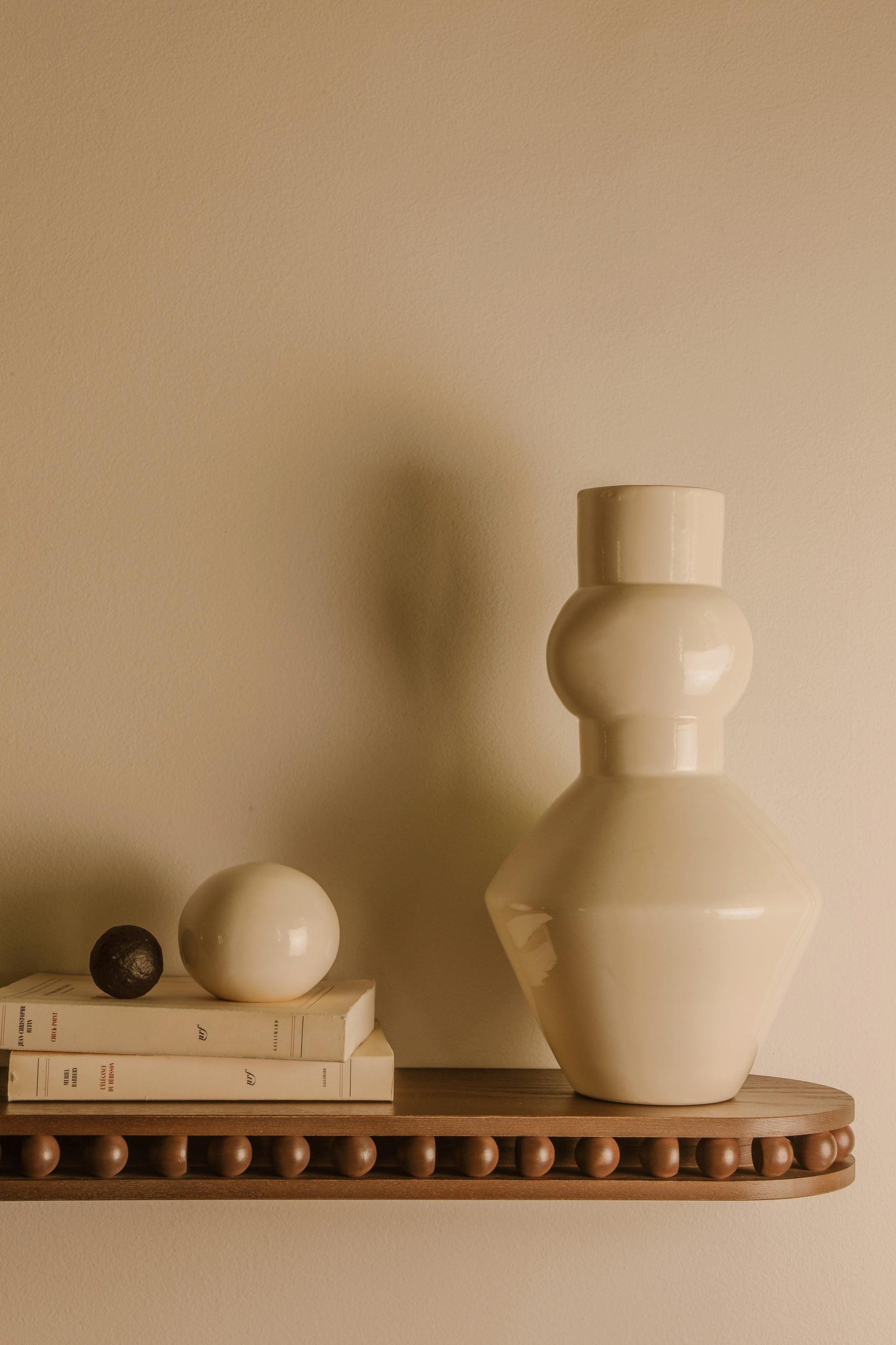 A fixer sur le côté d'un mur ou de chaque côté d'un lit comme chevet, l'étagère Léon est un petit bijou d’ébénisterie. Etagère en bois massif réalisé par un atelier artisanal français, pièce iconique de la collection Caroline Andréoni La Maison. Dans le détail, Caroline Andréoni est venue jouer avec les courbes et les sphères pour une pièce décorative et ornementale. Accompagnée du vase Pico, en faïence émailée made in France - céramique blanche tournée à la main par un potier en Normandie.