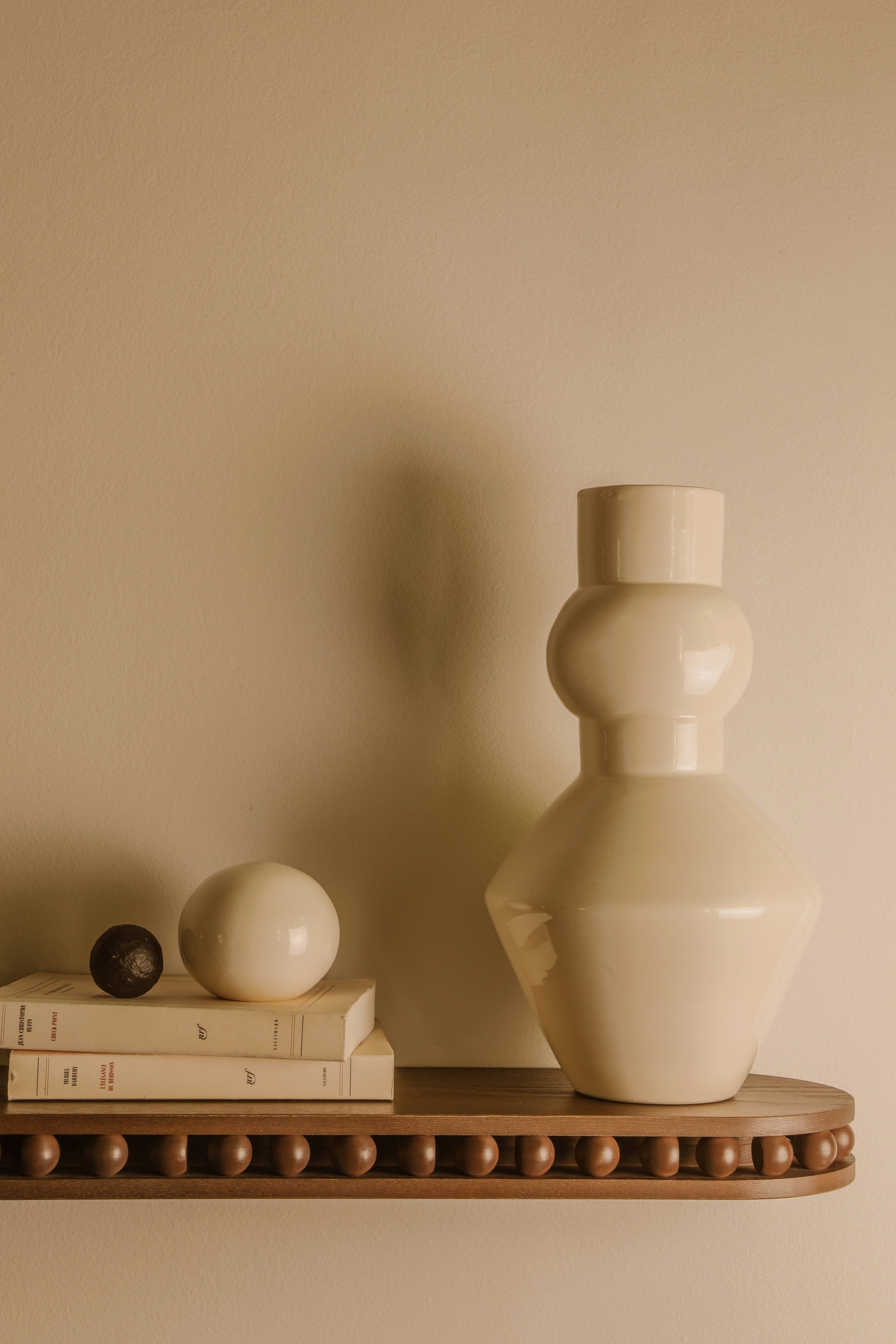 A fixer sur le côté d'un mur ou de chaque côté d'un lit comme chevet, l'étagère Léon est un petit bijou d’ébénisterie. Etagère en bois massif réalisé par un atelier artisanal français, pièce iconique de la collection Caroline Andréoni La Maison. Dans le détail, Caroline Andréoni est venue jouer avec les courbes et les sphères pour une pièce décorative et ornementale. Accompagnée du vase Pico, en faïence émailée made in France - céramique blanche tournée à la main par un potier en Normandie.